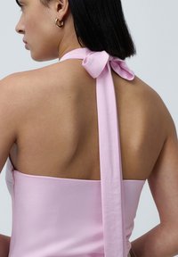 Rosa sateng halterneck-kjole med en sløyfe bak. Glatt tekstur, tettsittende liv og utringning på skuldrene for åpent ryggdesign.