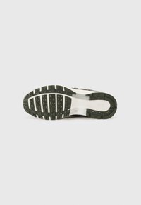 Nike tenisice s bijelim gornjim dijelom, zelenom potplatom, teksturiranim uzorkom za prianjanje i podstavljenim srednjim dijelom. Imaju logo sa strane i čvrstu konstrukciju.