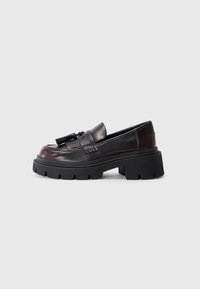Loafers negri masivi din piele netedă, cu un accent împletit și o talpă plată din cauciuc cu un model pronunțat de profil.