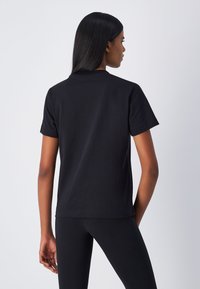T-shirt nero in cotone a maniche corte con collo tondo e vestibilità rilassata. Tessuto liscio senza decorazioni visibili o accessori.