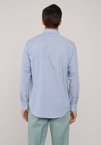 Blauw-wit gestreepte blouse met lange mouwen en een relaxed fit, met een knoopsluiting col en afgeronde zoom. De stof lijkt glad, met knoopmanchetten.