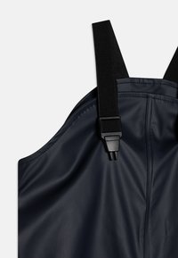 Marineblå vanntett smekke med justerbare svarte stropper og plastkomponenter. Har en glatt tekstur og avrundede kanter for en tettsittende passform.