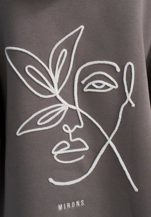 Tessuto grigio con ricami bianchi che raffigurano il disegno di un volto e una foglia. Il testo "MIRONS" è ricamato sotto il design. Texture liscia, stile minimalistico.