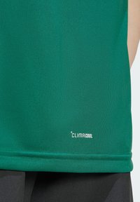 Grønn ClimaCool-skjorte med en glatt, fukttransporterende tekstur. Har en litt avrundet kant og en liten hvit logo nær bunnen.