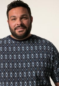 Svetr s námořnickým vzorem, který zobrazuje diamantové tvary v modré a bílé barvě s kulatými akcenty a kulatým výstřihem. Viditelná jemná textura látky.