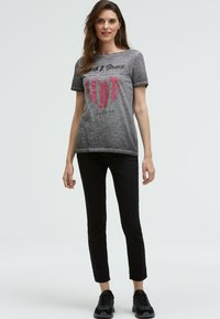 Gray short-sleeve t-shirt with "LOVE" graphic in pink and black lettering. Paired with black skinny jeans and black sneakers. Simple design.