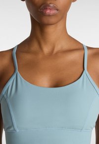 Lichtblauw sporttopje met dunne bandjes, naadloos ontwerp en een getailleerde pasvorm. Glad textuur met minimale stikseldetails.