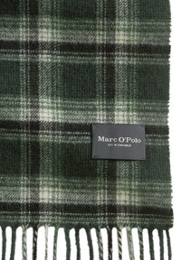 Écharpe en laine à carreaux dans des tons de vert foncé, vert clair et noir. Présente des bords à franges et une étiquette en tissu noir portant la marque "Marc O'Polo".