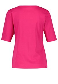 Camiseta de manga corta y cuello redondo en algodón rosa vibrante. Textura suave, corte holgado, bajo recto. No hay patrones ni detalles adicionales visibles.