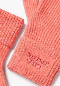 Gants tricotés en corail vif avec une texture côtelée. Présente un logo "Super Dry" brodé sur le poignet. Tissu doux et chaud.