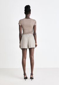 Light brown fitted t-shirt and light gray elastic waistband shorts. The shorts have a textured fabric and a relaxed fit, ending above the knees.