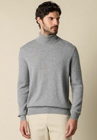 Maglione grigio a collo alto realizzato in morbido tessuto knit, caratterizzato da maniche lunghe e polsini e orlo a coste. Design minimalista con una texture liscia.