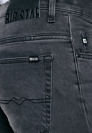 Close-up af baglomme på mørkegrå denimjeans med Big Star-mærkat og synlig syning.