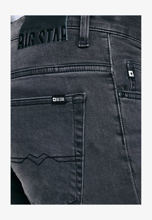 Close-up van de achterzak van een donkergrijze spijkerbroek met het merklabel Big Star en een gestikte designdetail.