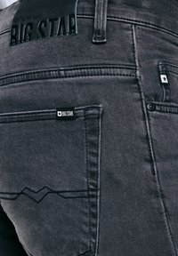 Nahaufnahme der Gesäßtasche einer dunkelgrauen Jeans mit dem Markenschild Big Star und einer gestickten Designverzierung.