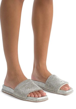 Platte slidersandalen met een brede, sprankelende zilveren bovenkant. Zacht textuur op de zool, met gedetailleerde rhinestone-versieringen langs de banden.