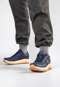 Granatowe buty sportowe z teksturowaną powierzchnią, kremową podeszwą środkową i gumową podeszwą. Wyposażone w okrągłe sznurówki i logo na języku.