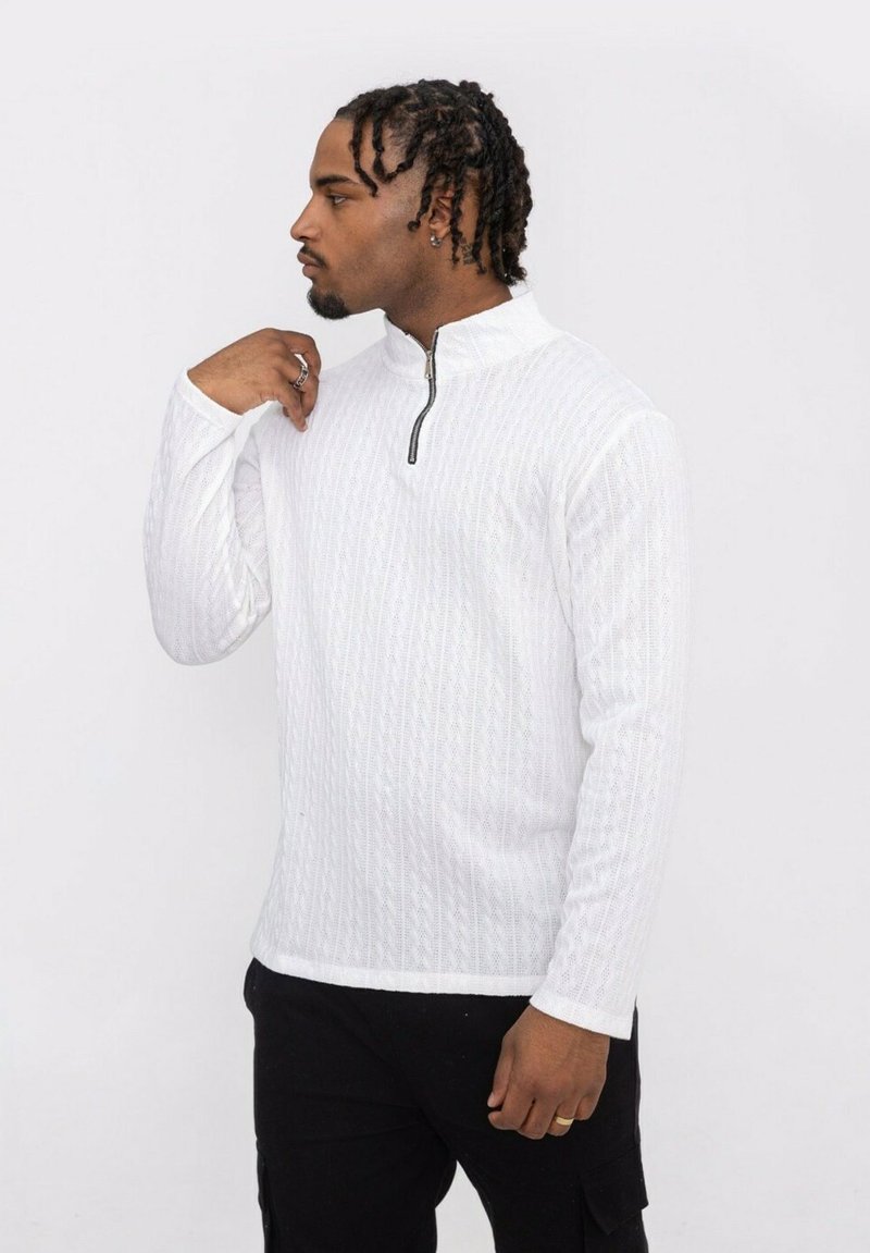 Pull blanc avec un col haut, doté d'une fermeture éclair et d'un motif en relief en forme de diamant. Le tissu semble doux et léger.