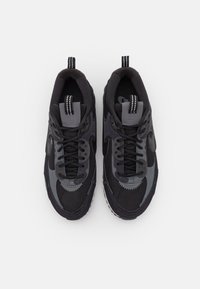 Czarne i szare sportowe buty, wykonane z materiałów siatkowych i gumowych, z teksturowanymi akcentami oraz kontrastującymi sznurówkami. Posiadają pętelkę na pięcie.