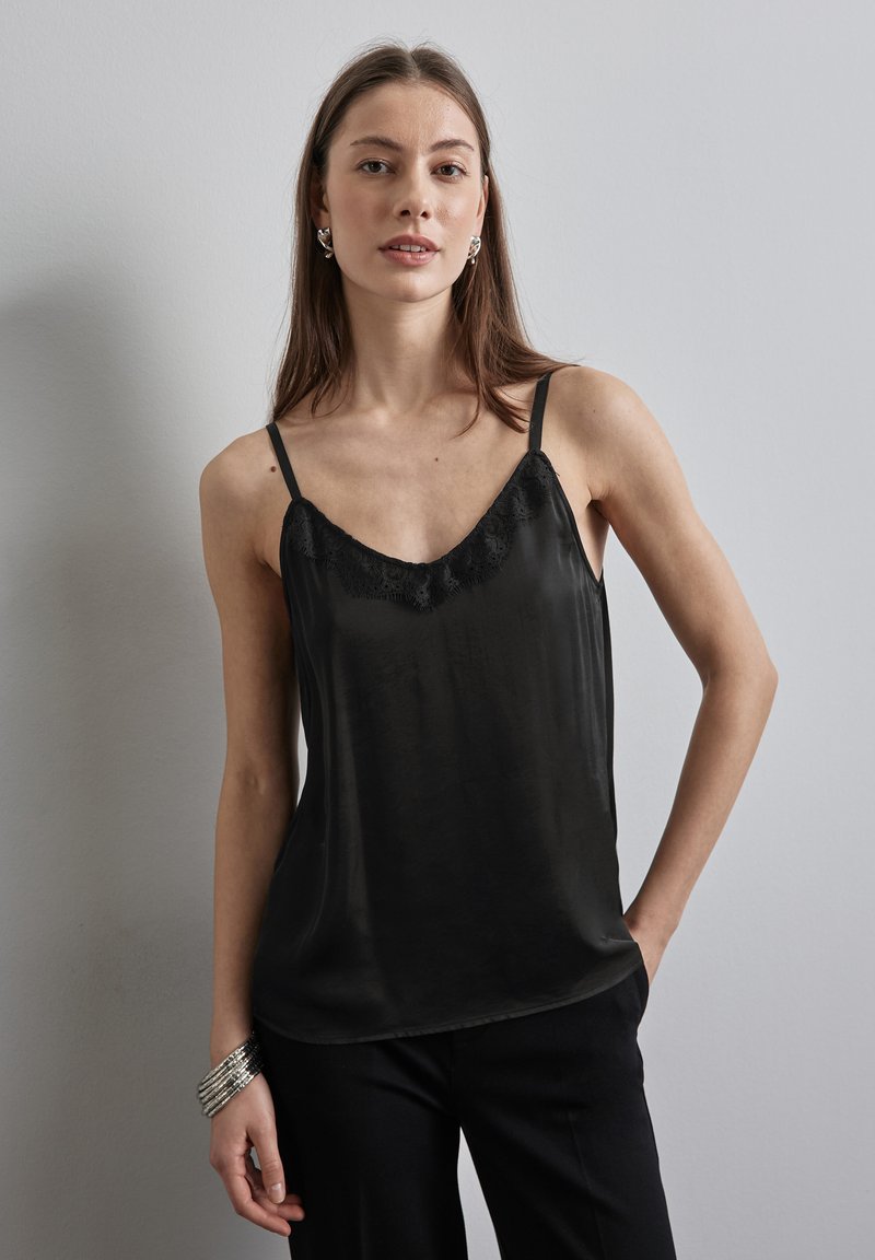 Zwarte satijnen camisole met kanten rand langs de halslijn, dunne verstelbare schouderbanden en een vloeiende silhouet. Gekocht met zwarte broek.