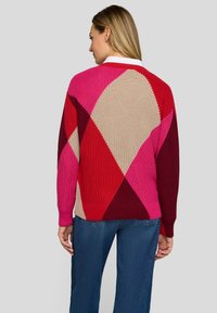 Gestrickte Strickjacke mit geometrischem Muster in den Farben Pink, Rot, Beige und Burgunder. Rippenbündchen an Ärmeln und Bund runden das Design ab.