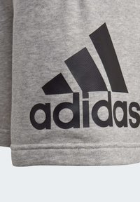 Pantalones cortos de algodón gris con un destacado logo negro de Adidas y tres rayas diagonales en la esquina superior izquierda.