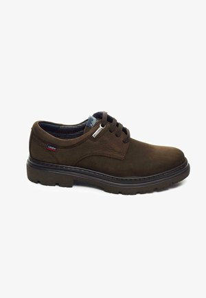 Zapatos de cuero marrón oscuro con una textura suave, punta redondeada y suela de goma. Presentan cordones clásicos y una pequeña etiqueta de logo en el costado.