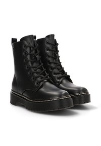 Botas de tobillo de imitación de cuero negro con cordones en la parte delantera, suela de plataforma texturizada y detalle de costura blanca en contraste.