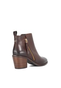 Brown leather ankle boot featuring a side zipper with gold hardware, stacked heel, and a pull tab at the back. Smooth texture with a polished finish.