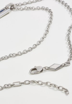 Collier chaîne en métal argenté avec maillons ovales et fermoir mousqueton sur fond blanc.
