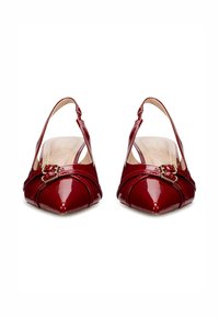 Pantofi slingback din piele patent roșie cu vârful ascuțit, având un accent din cataramă aurie și detalii cusute în cruce pe față.