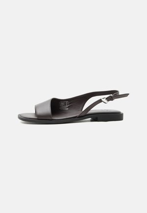 Black leather flat slingback sandal with open toe and adjustable silver buckle strap against white background.