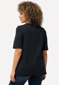 Černé tričko s krátkým rukávem a kulatým výstřihem, volnější střih a měkká textura; má mírně delší zadní lem.