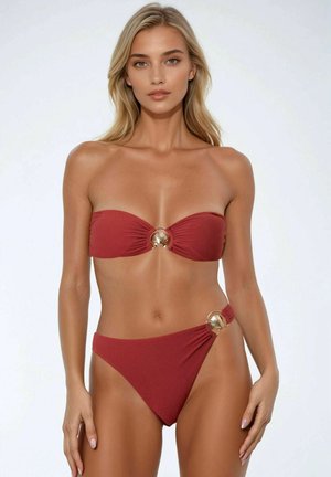 Bikini set in diep rood met een bandeau-top en gouden schelpaccenten. De high-waisted onderkant heeft een textuurstof en een unieke zijdetail.