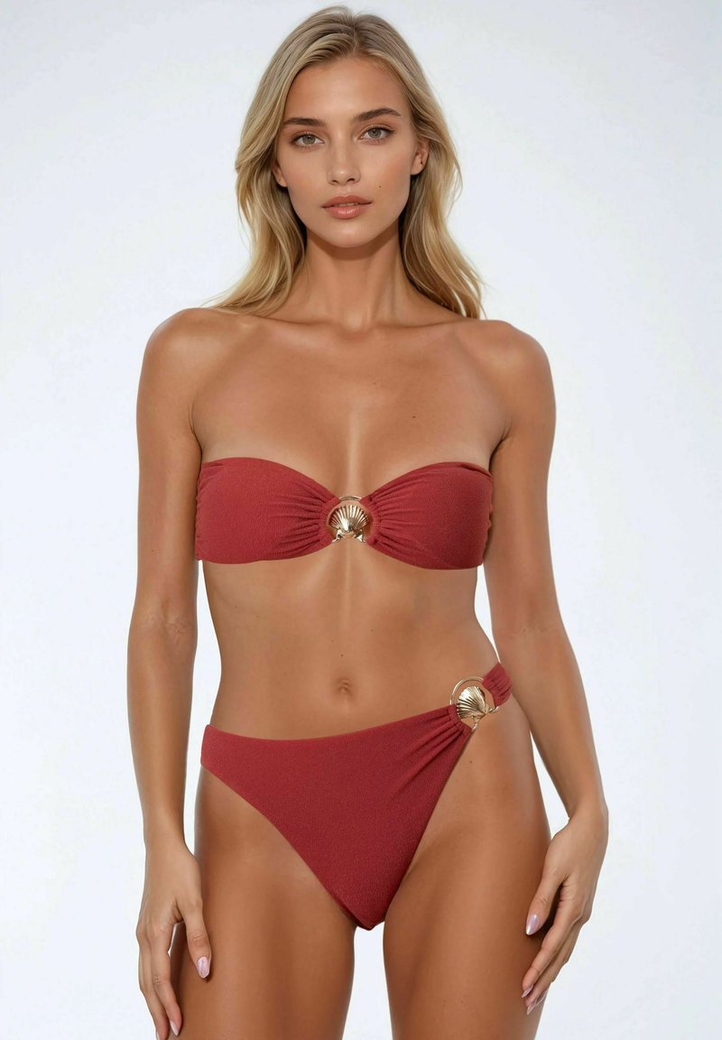 Bikini set in diep rood met een bandeau-top en gouden schelpaccenten. De high-waisted onderkant heeft een textuurstof en een unieke zijdetail.