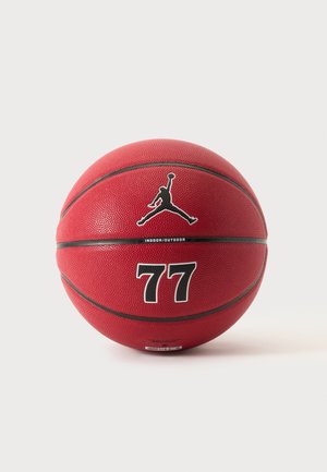 Piros kosárlabda fekete vonalakkal, Jordan logóval, "77"-es számmal és „Indoor/Outdoor” szöveggel egyszerű világos háttéren.
