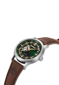 Orologio automatico con quadrante verde, indici delle ore dorati, cassa in acciaio inossidabile e cinturino in pelle marrone con logo in rilievo.