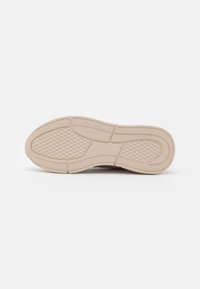 Sole of a shoe, light beige rubber with a textured surface. Features raised patterns and distinct sections for traction and support.