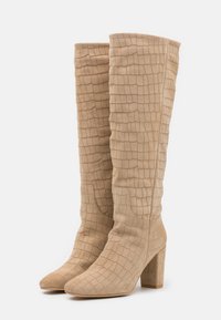Bottes beige mi-mollet en daim texturé, avec un motif carré, un bout pointu et un talon épais.