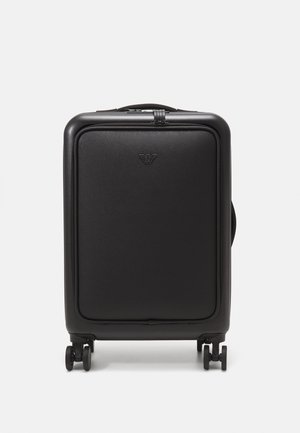 Juodas kietas lagaminas su tekstūruotu paviršiumi, su priekinėmis logotipo detalėmis, ratukais mobilumui ir tvirtu viršutiniu rankena.