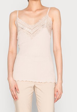 Beige ribbet camisole med delikat blonderkant og skåret kant. Har tynde justerbare stropper og en tætsiddende silhuet.