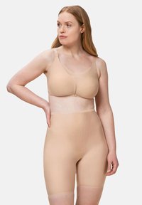 Sujetador beige y pantalones moldeadores de tejido liso y elástico. El sujetador tiene tirantes anchos y un diseño de escote en V; los pantalones presentan un corte sin costuras y de cintura alta.