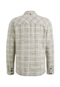 Chemise à manches longues avec motif à carreaux blancs et noirs, poignets boutonnés et petit détail rond au centre haut du dos.