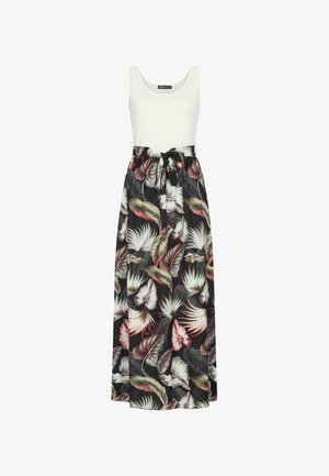 La robe maxi présente un haut ajusté blanc et une jupe fluide noire ornée d'un imprimé de feuilles tropicales éclatantes en verts, rouges et blancs. Détail à la taille nouée.