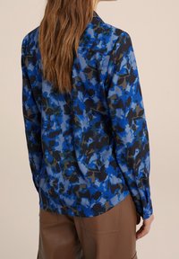 Camicia a stampa floreale blu con maniche lunghe, realizzata in tessuto leggero. Caratterizzata da una textura liscia e un design a colletto classico.