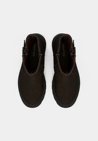 Botines marrones hasta el tobillo con acabado de cuero liso, suelas de caucho y cremallera lateral. Presentan un diseño minimalista y sutiles detalles de costuras.