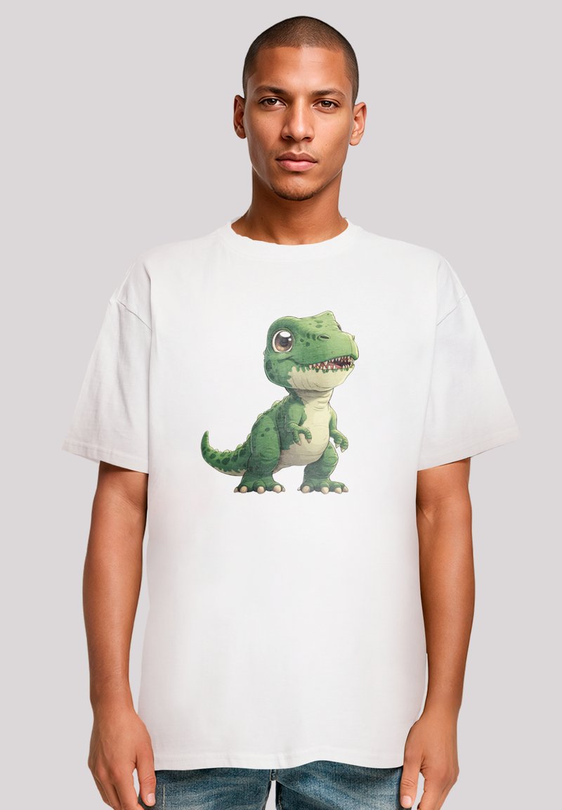 White cotton t-shirt featuring a colorful illustration of a green dinosaur with big eyes and textured scales, printed on the front.