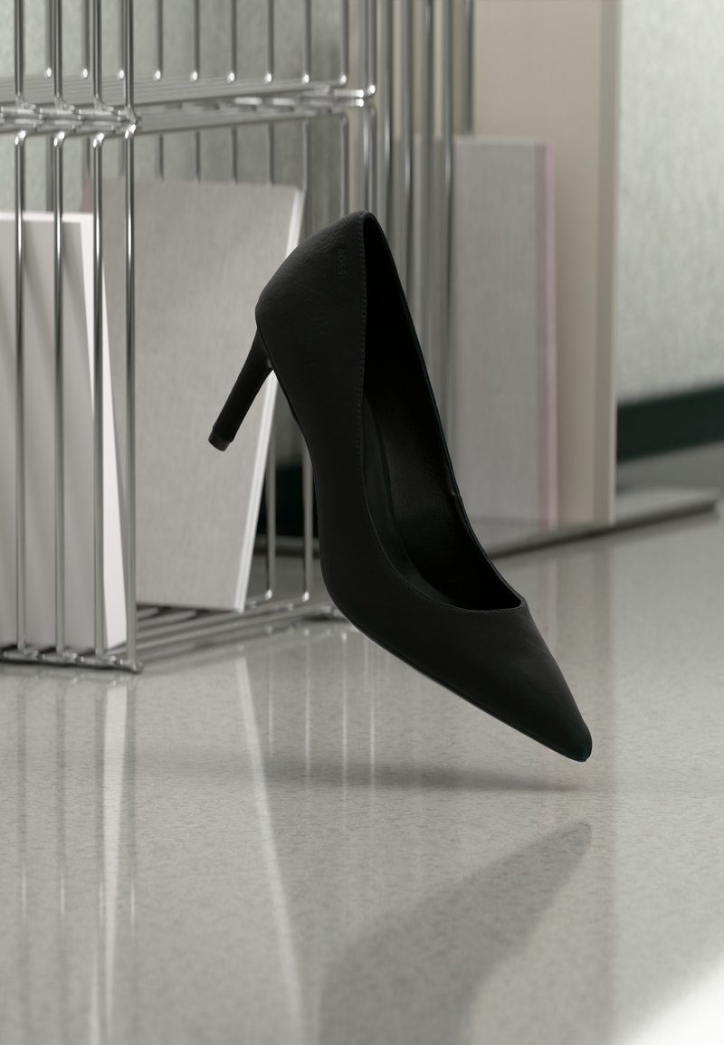 Μαύρο γυναικείο παπούτσι με ψηλό τακούνι ισορροπημένο στην φτέρνα του πάνω σε μια ανακλαστική επιφάνεια κοντά σε μεταλλικά ράφια αρχειοθέτησης με λευκούς φακέλους.