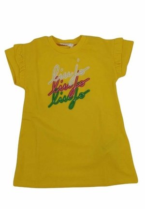 Camiseta de algodón amarilla con mangas cortas y volantes, y texto bordado multicolor. Los colores del texto incluyen blanco, rosa, rojo y verde.