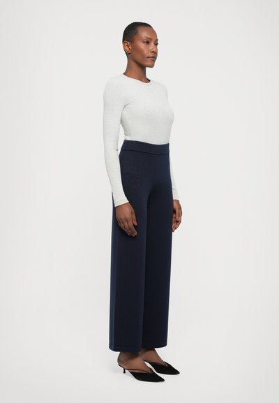 Navy high-waisted wide-leg trousers paired with a light gray fitted long-sleeve top. Smooth texture, minimalist design, and sleek silhouette.
